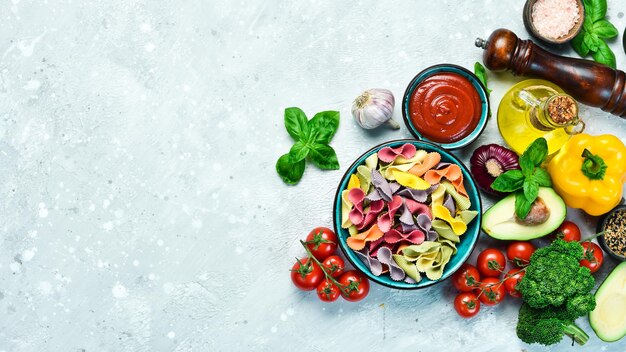 Colored dry pasta in a bowl on a gray stone background Food Top view Free space for text