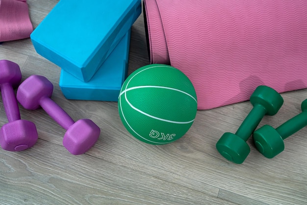 Colored dumbbells for sports ball with sand sneakers gum for sports and cubes spread out on the spacious floor Sport concept The concept of sports equipment