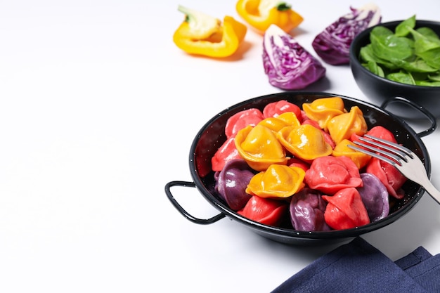 Colored dumplings in frying pan and vegetables on white background space for text