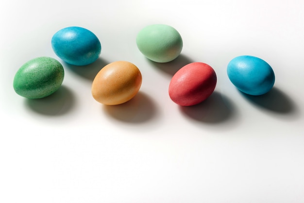 Colored easter eggs lie on a white background, casting shadows.