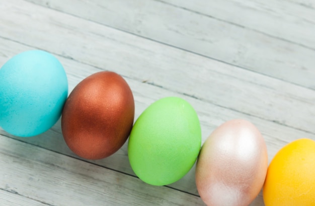 Colored Easter eggs on a light wooden background.