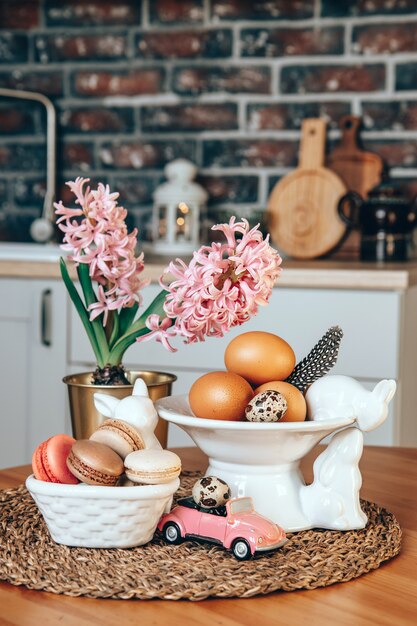 컬러 부활절 달걀, 마카롱 케이크, 핑크 히아신스와 도자기 부활절 토끼는 테이블에