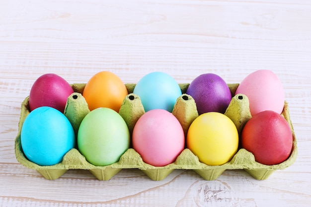 Colored Easter eggs in a pan, on a white wooden table.
