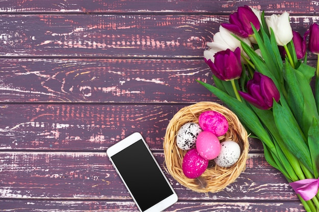 Colored easter eggs, tulip flowers and smartphone