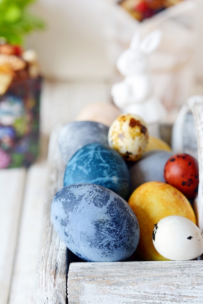 Photo colored easter eggs in a wooden basket on a white background. happy easter. easter decoration.