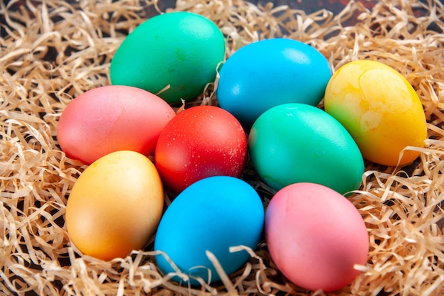 Colored eggs laid up side by side in three rows on yellow straw