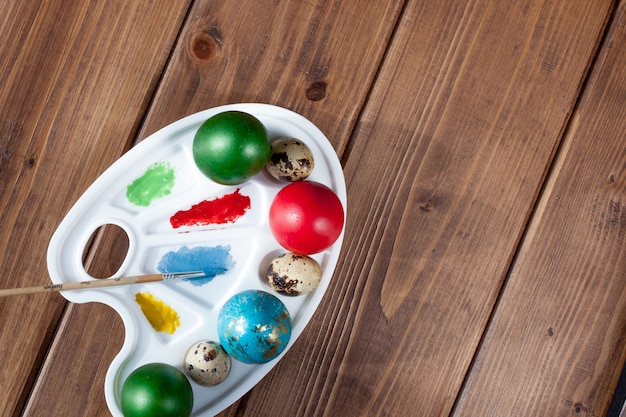 Foto uova e pittura colorate su una tavola di legno, fondo di pasqua