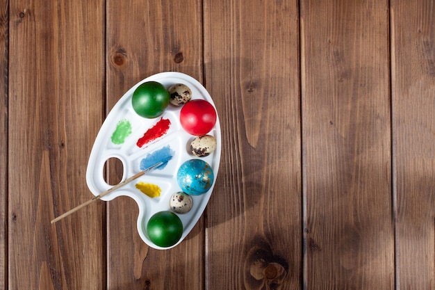 Photo colored eggs and paint on a wooden table, easter background