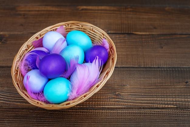 Colored eggs in a wicker basket. Concept Happy Easter.