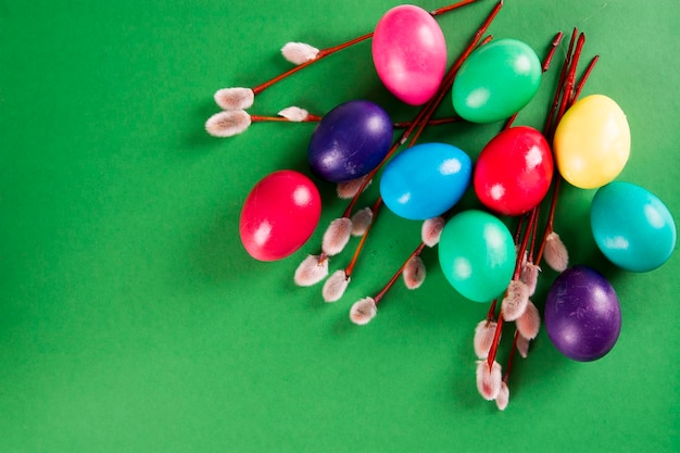 Colored eggs and willow branches on a green background Happy Easter