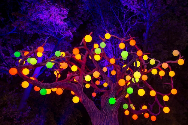 Colored glowing balls of garlands on a tree in a city park Celebration decoration of the festival