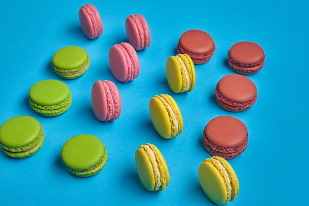 Colored macaron or macaroon sweet meringuebased confection on blue background Closeup copy space