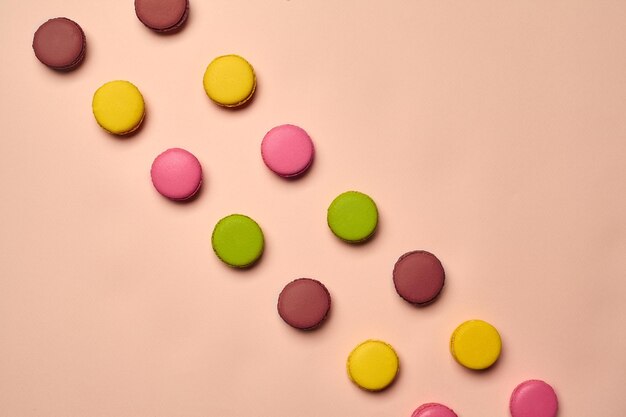 Colored macaron or macaroon sweet meringuebased confection on pink background Closeup copy space