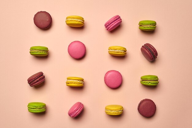 Colored macaron or macaroon sweet meringuebased confection on pink background Closeup copy space