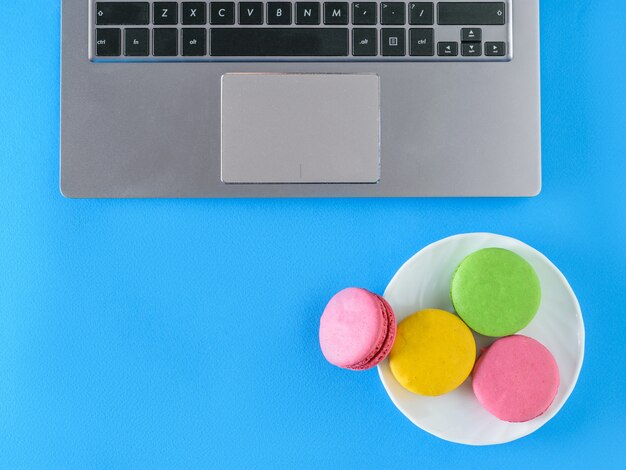 Colored macarons in a plate bowl with the computer