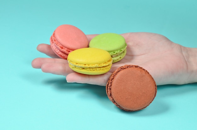 Colored macaroons in hand close-up on a blue surface