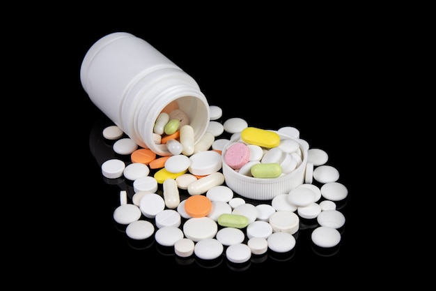 黒いテーブルの上の着色された医薬品と丸薬