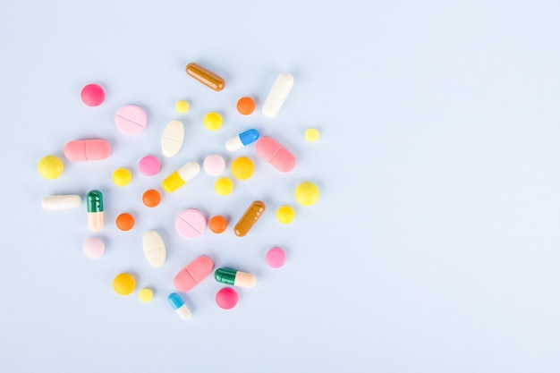 colored medical pills and capsules on a blue background