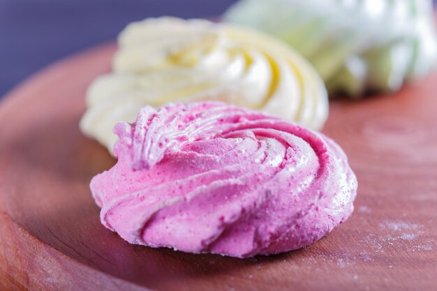 Colored meringues on wooden board.