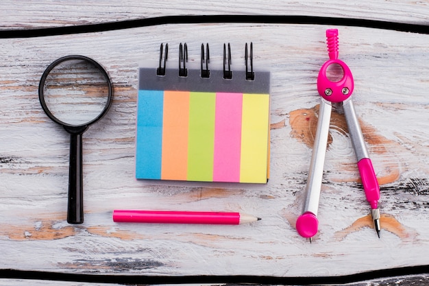 Colored notepad with pink pencil and dividers. School accessories on white wooden table.