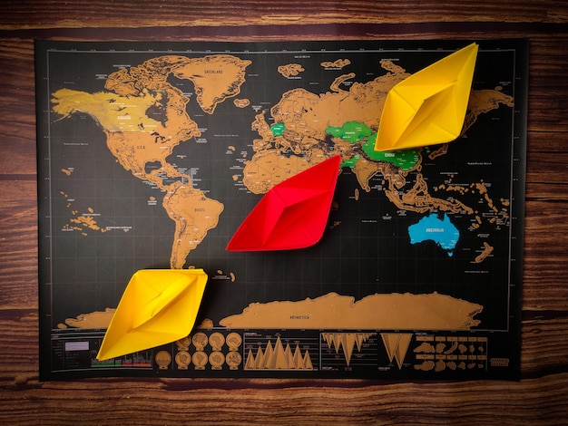 Colored paper ship and world map on a wooden table