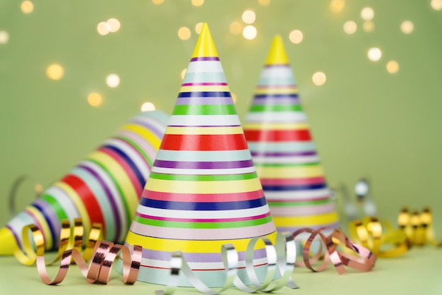 Photo colored party hats for holiday party on green background copy space closeup