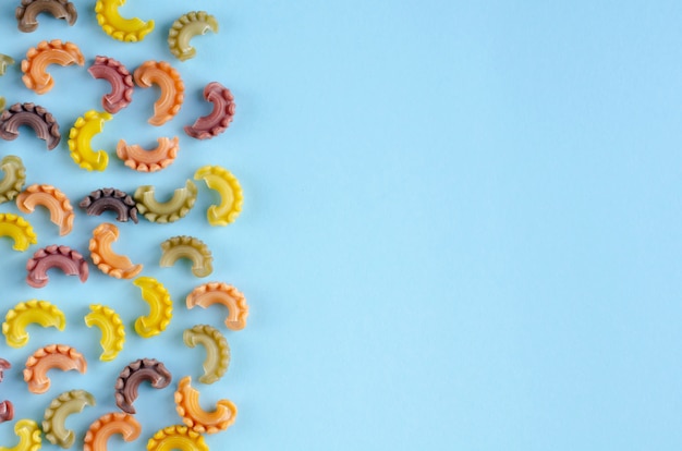 Colored pasta composition on blue background. Flat lay