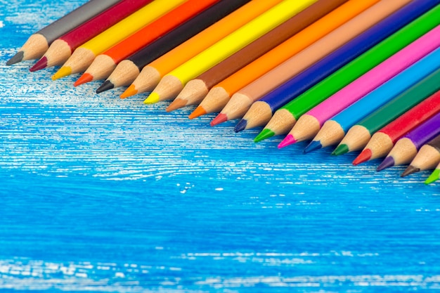 Colored pencils are on a blue Board.