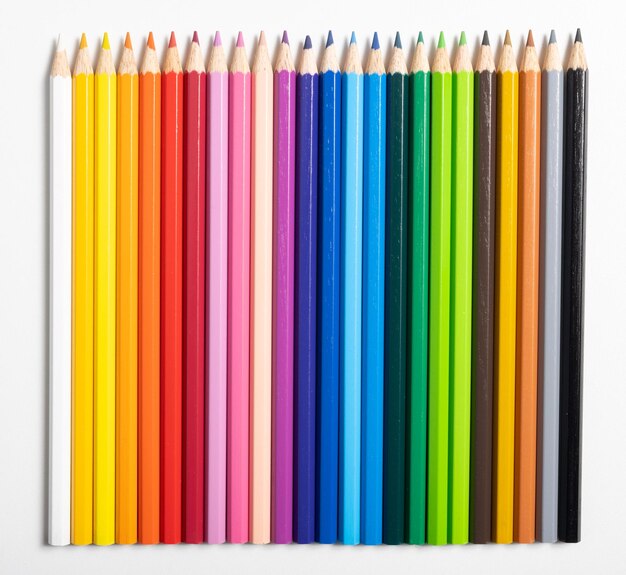 Colored pencils of different colors lined up on white background