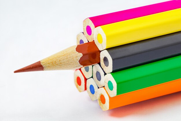 Концы цветных карандашей не заточены коричневой точилкой для карандашей на белом фоне, выборочный фокус