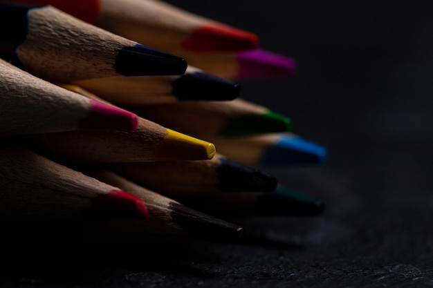 Colored pencils lie on a dark background