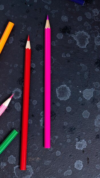 цветные карандаши лежат на темном фоне