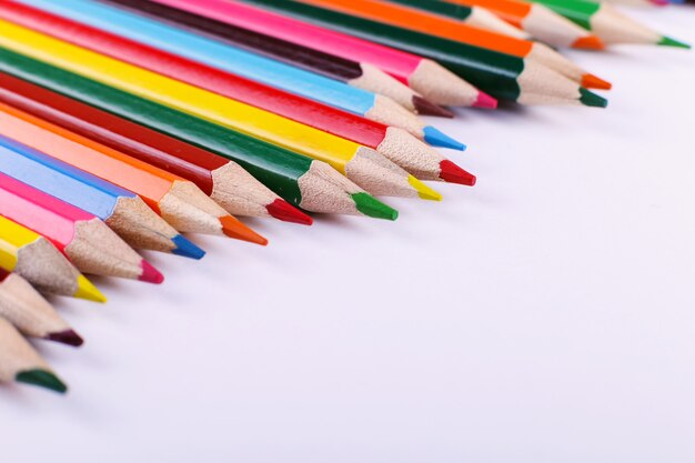 Colored pencils lie in a row on white