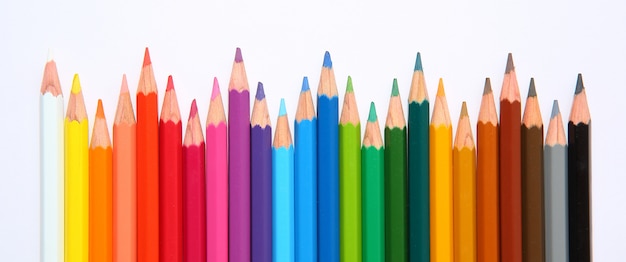 Colored pencils row with wave on white background