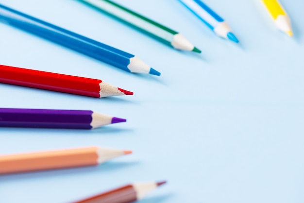 Colored pencils in a semicircle on a blue background