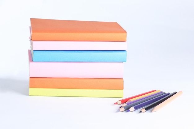 Colored pencils and stack of books on white background photo with copy space