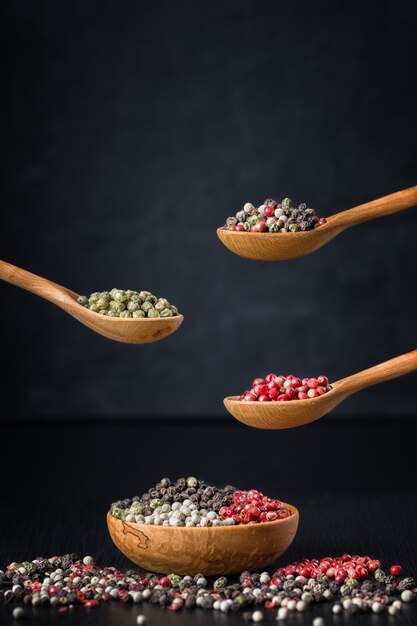 Colored pepper in a wooden spoon on dark