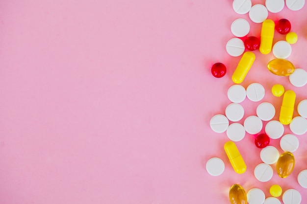 Pillole colorate e capsule sul rosa.