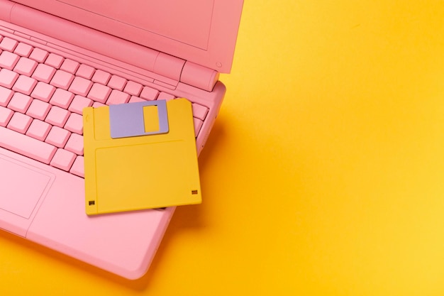 Colored pink laptop with bright floppy disk modernity concept