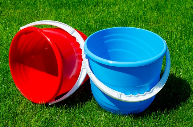 Colored plastic garden buckets on of green grass