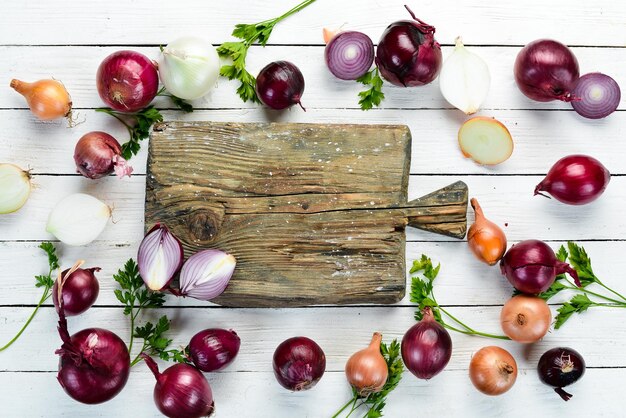 Colored ripe onions on wooden board on white wooden background Top view Free copy space