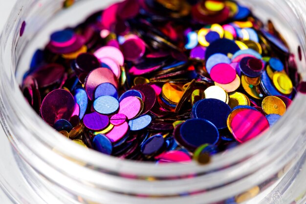 Colored sequins in a plastic jar closeup