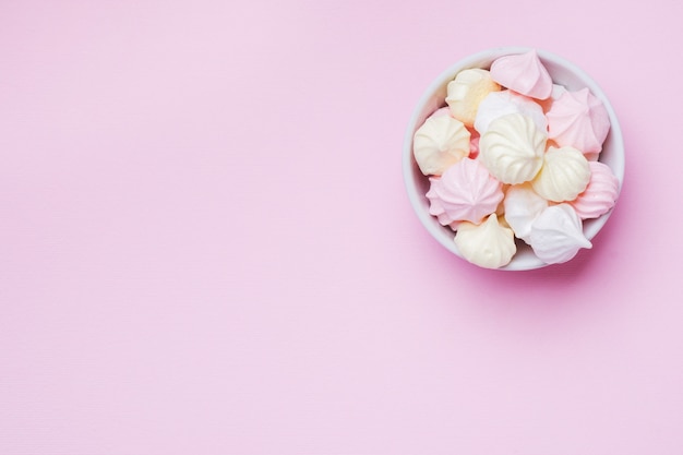 Colored small meringues on pink. Flat lay concept. Copy space.