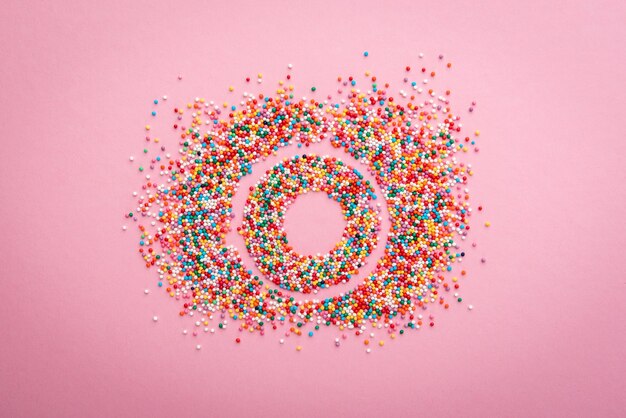Photo colored sprinkles on pink background.