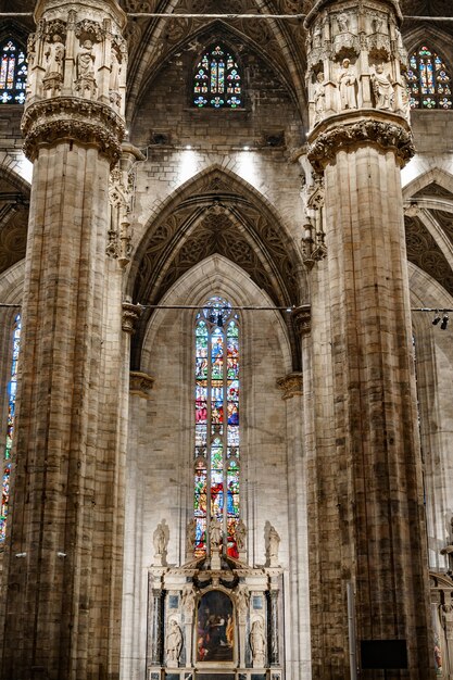 Colored stained glass windows against the huge carved marble columns of the duomo italy milan