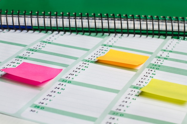 Colored sticky notes on a work agenda in a close up viw