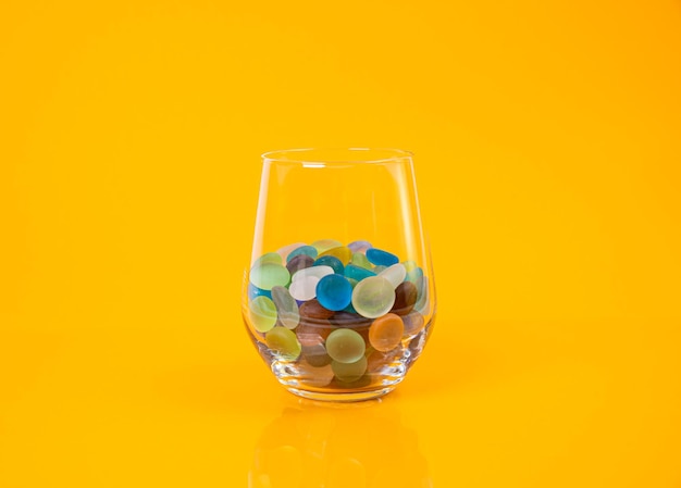 Colored stones in glass in jar in bucket on orange background