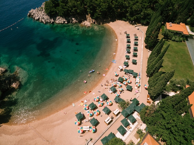 Colored sun umbrellas stand on the sand at the royal beach in przno view from above