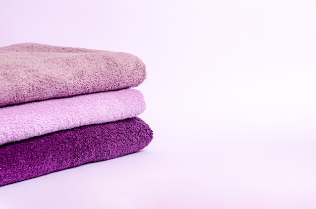 Colored terry bath towels folded on a white background. A stack of cotton towels with a place for your text. Close-up.