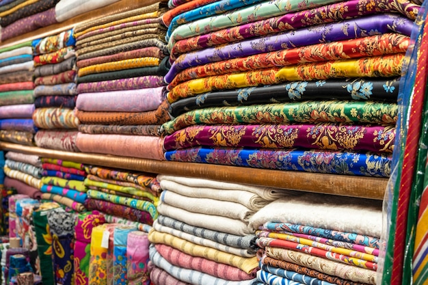 Цветной текстиль или ткань на уличном азиатском рынке, полки с рулонами ткани и текстиля